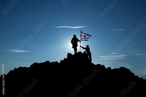 Two unrecognizable   soldiers raise the Greek flag photo