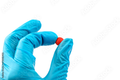 Hand doctor in medical blue gloves hold red pill. Pill Research Concept.