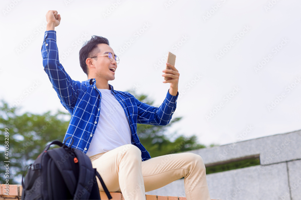 excited young asian man sitting on stairs and using smart phone Stock ...