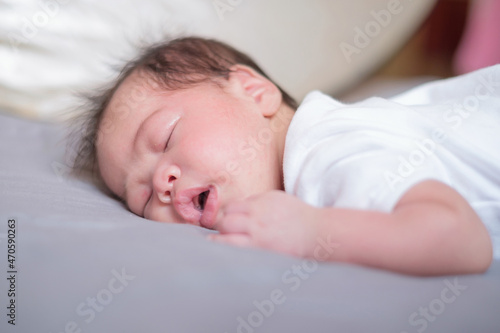 Asian baby sleeping on gray bed