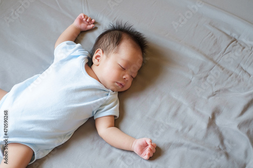 Asian baby sleeping on gray bed