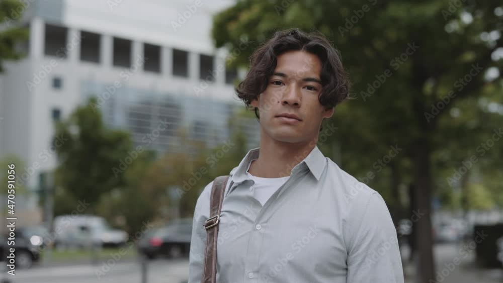 Asian businessman using mobile while posing on street