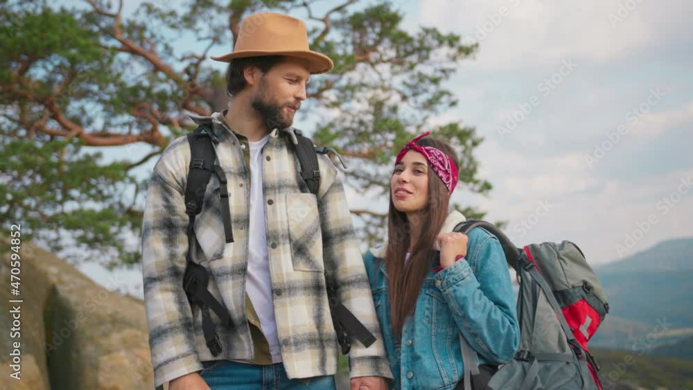 Handsome young man with his girlfriend hiking in the mountains. Smiling joyful travel couple family admiring cinematic landscape views on clifftop. Portraits. Handsome young man with his girlfriend hiking in the mountains. Smiling joyful travel couple family admiring cinematic landscape views on clifftop. Portraits.
