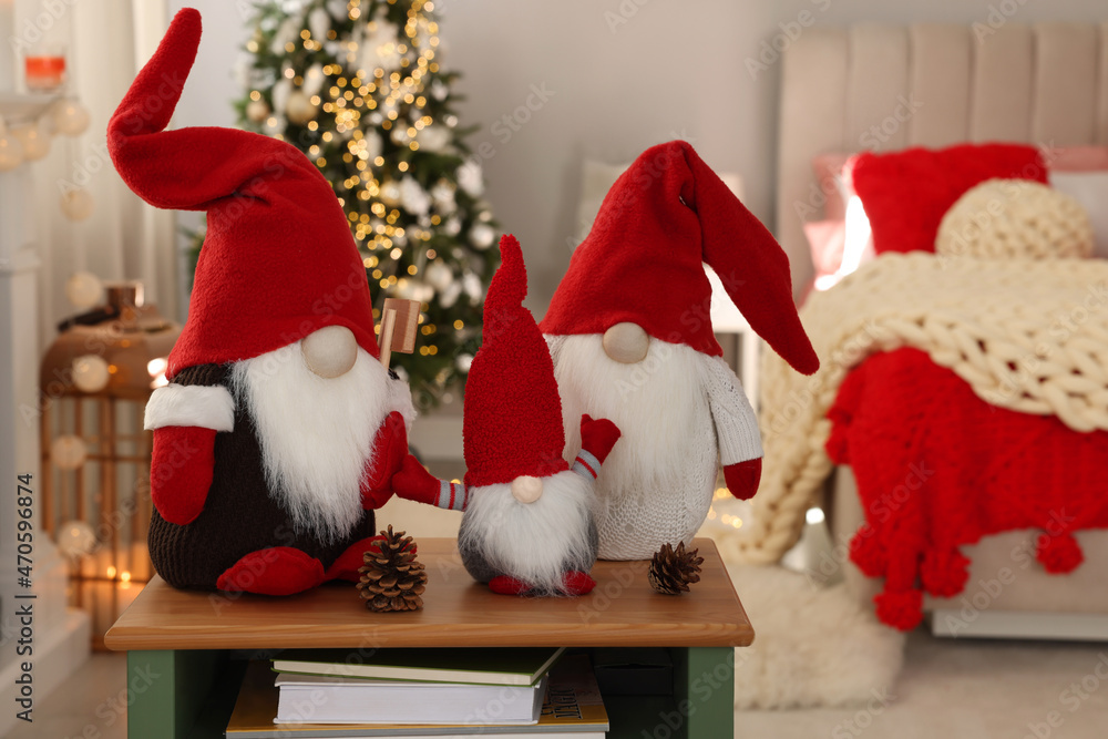 Obraz premium Cute Christmas gnomes on wooden table in room with festive decorations
