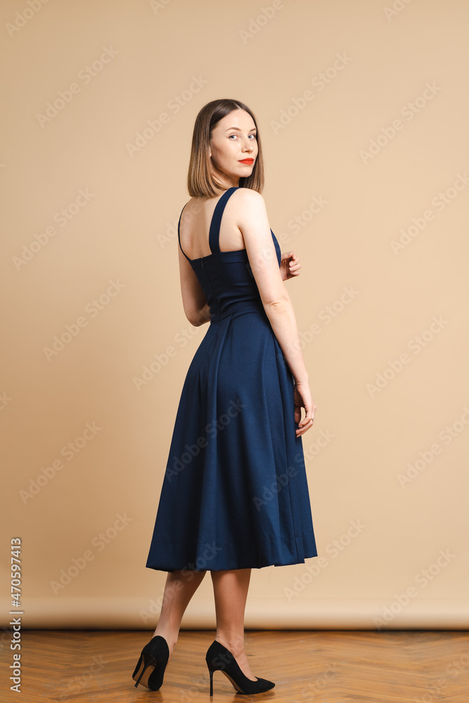 Beautiful woman pretty face bright face care dark blonde hair wear clothes short blue dress on beige background Beautiful woman pretty face bright face care dark blonde hair wear clothes short blue dress on beige background