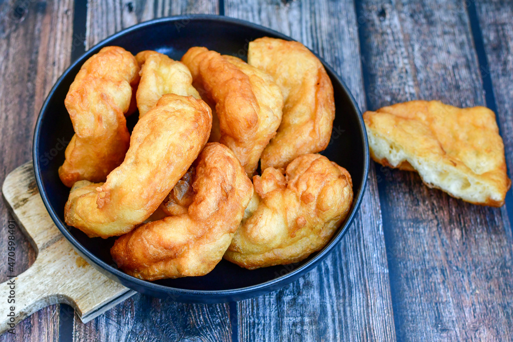 Traditional Bulgarian home made deep fried patties covered with sugar оn rustic backgroud.Mekitsa or Mekica, on wooden rustic background. Made of kneaded dough that is deep fried Traditional Bulgarian home made deep fried patties covered with sugar оn rustic backgroud.Mekitsa or Mekica, on wooden rustic background. Made of kneaded dough that is deep fried