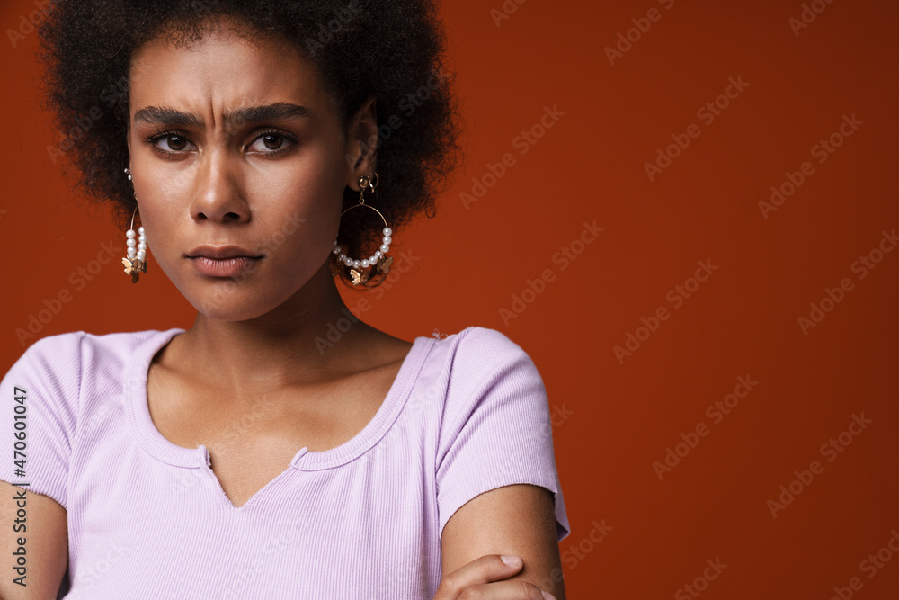 Young black woman wearing earrings frowning and looking at camera Young black woman wearing earrings frowning and looking at camera