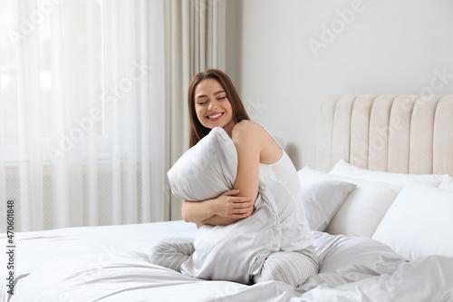Quadro su tela Young woman hugging pillow on comfortable bed with silky linens
