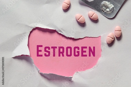 Torn paper hole with the inscription ESTROGEN and pills. Hormonal imbalance, women's reproductive health issues concept. photo
