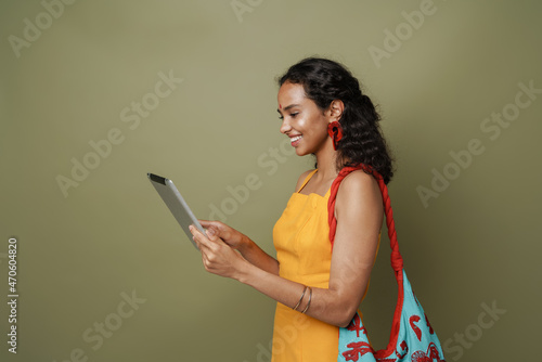Young south asian woman in dress smiling while using tablet computer