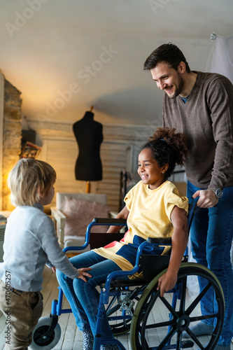 Happy multiethnic family. Smiling little girl with disability in wheelchair at home