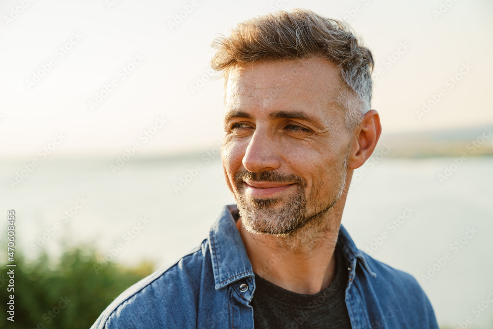 Grey man smiling and looking aside while standing outdoors Grey man smiling and looking aside while standing outdoors