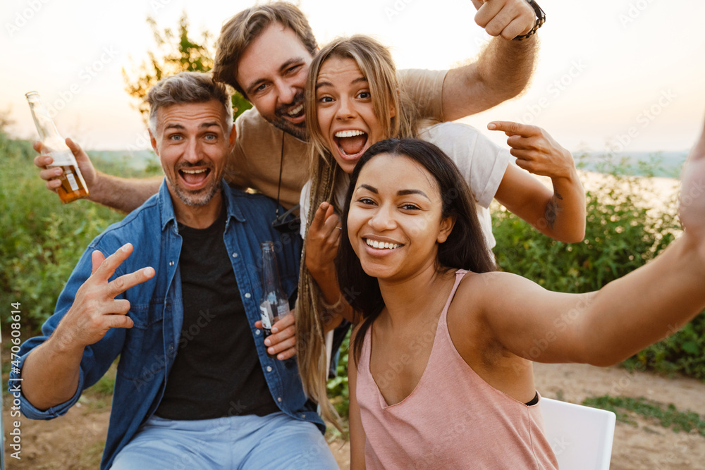 Multiracial two couples taking selfie while leaning on trailer