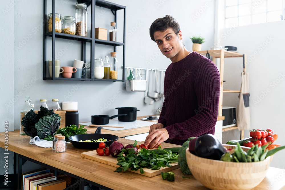 Young cutting vegetables while preparing food in kitchen Young cutting vegetables while preparing food in kitchen