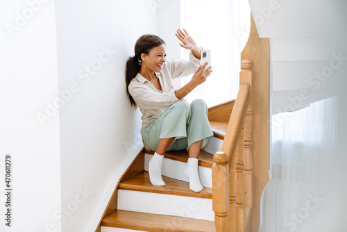 Young black woman using mobile phone while sitting on wooden stairs