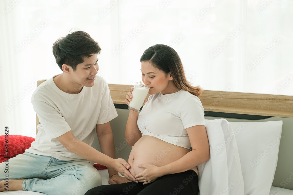 Asian man take care pregnant woman and drinking milk Asian man take care pregnant woman and drinking milk