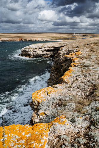 Sea cape. Colorful shot of the seascape. Thick sea foam and bright blue water. Rocks covered with moss. Obese sky overhead. OTdykh by the sea photo