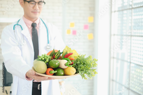 Professional nutritionist asia man holding fresh vegetables in clinic room