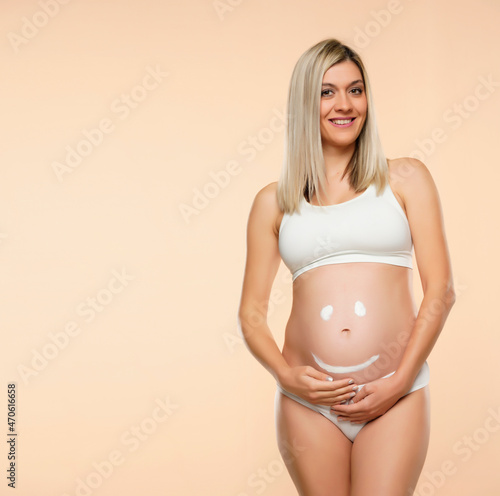 Future mother posing with a smiley face drawing on her belly © vladimirfloyd
