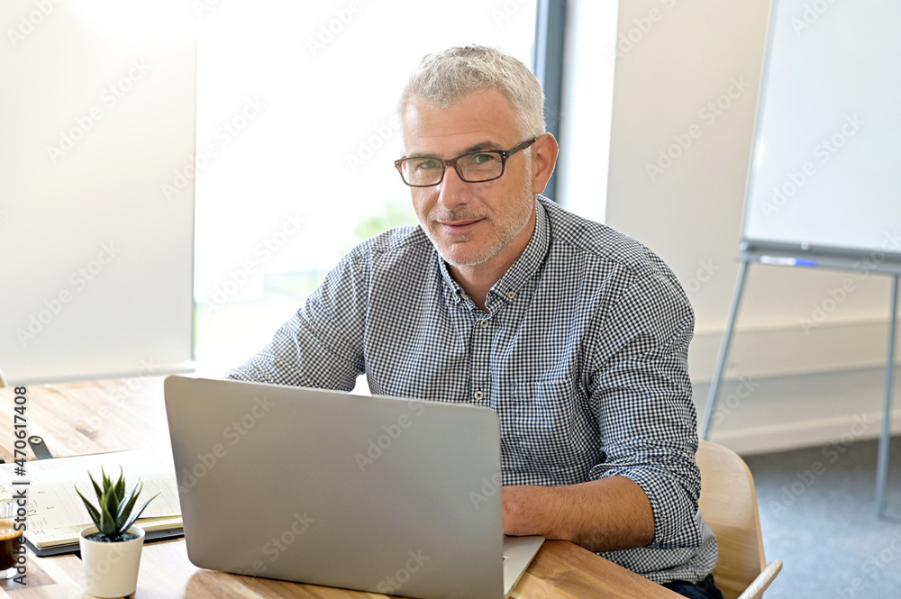 Businessman in co-working office sitting at table using laptop Businessman in co-working office sitting at table using laptop
