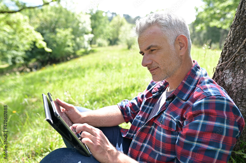 Obraz premium Man with grey hair and connected on digital tablet at home
