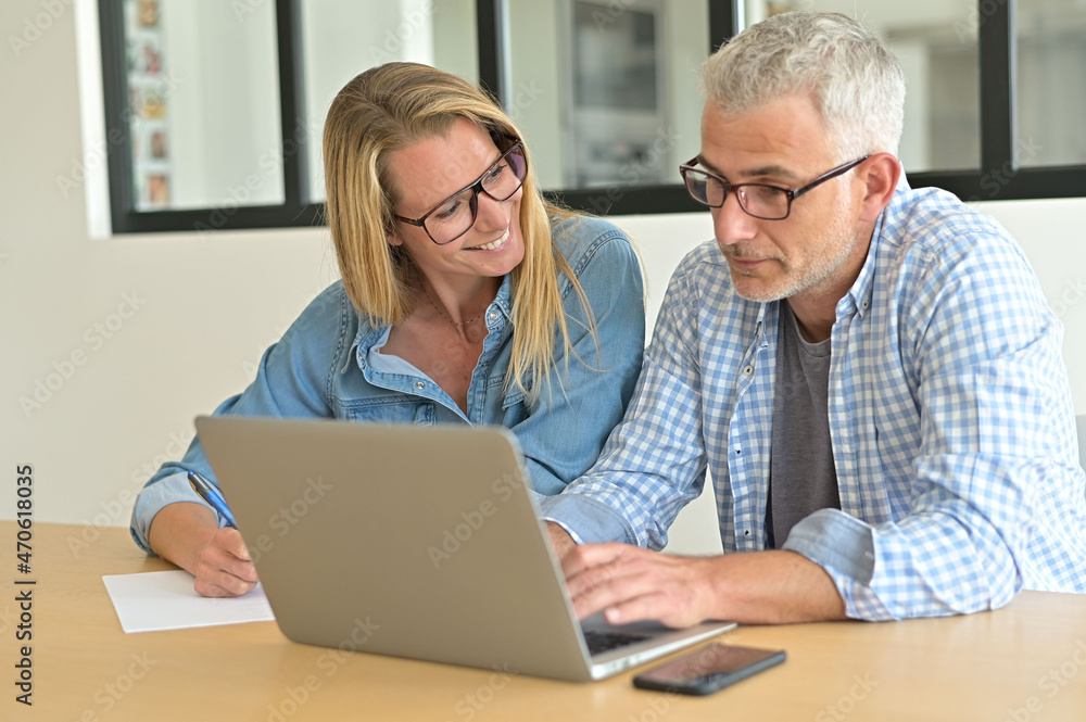 Couple with eyeglasses connected with laptop computer at home