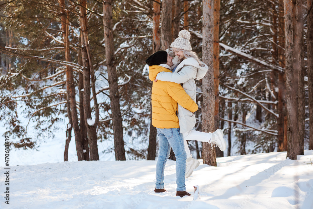 Good-looking couple is having fun in winter forest, spending Christmas holidays outdoors.