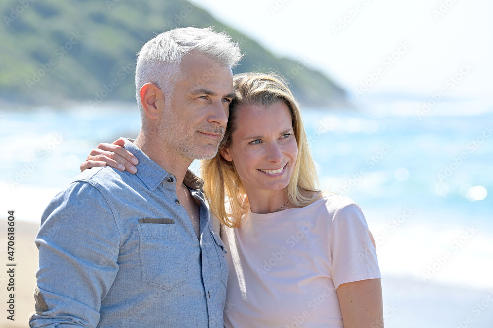 Middle-aged couple walking on a sandy beach Middle-aged couple walking on a sandy beach