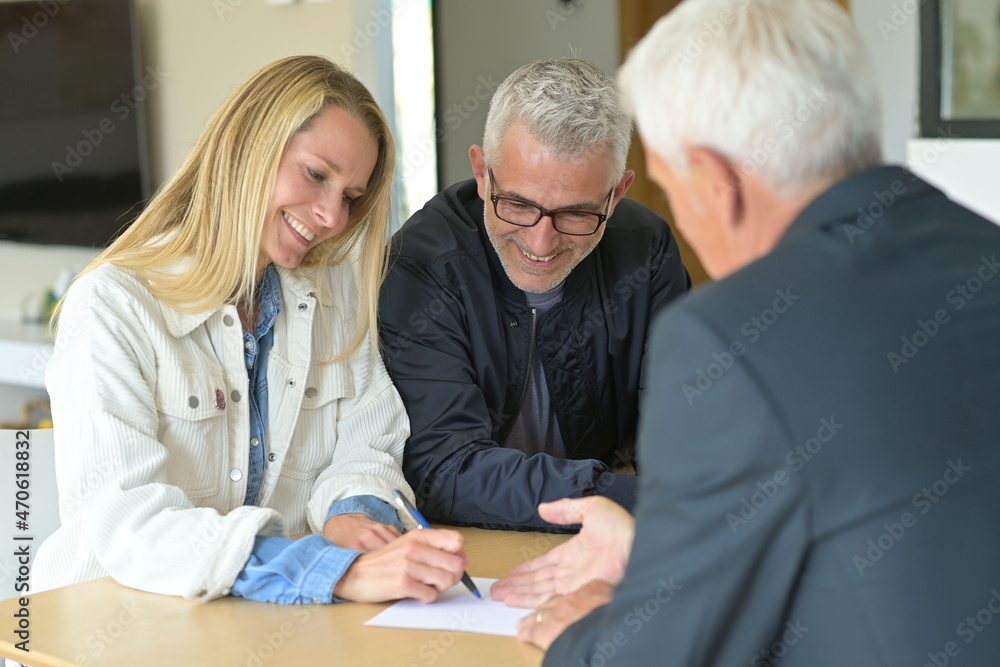 couple signing contract with real estate agent couple signing contract with real estate agent