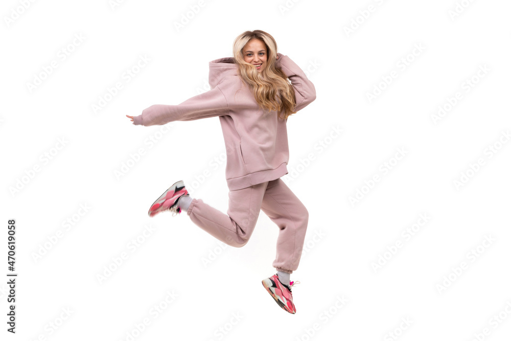 young woman in a jump on a white background in a pink sports suit