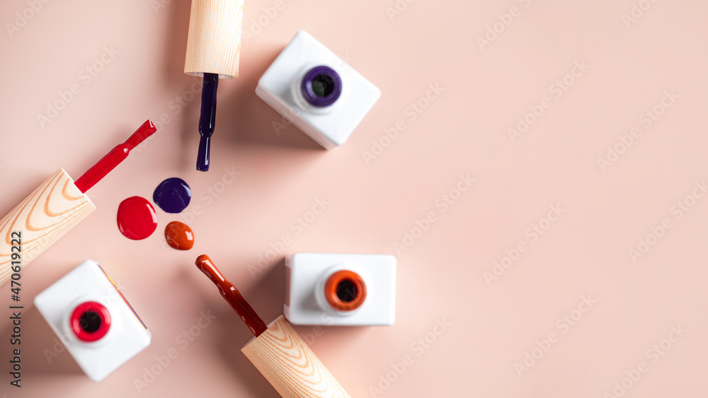 Different color brushes of bright nail polish bottles on light pink background. Copy space. Different color brushes of bright nail polish bottles on light pink background. Copy space.