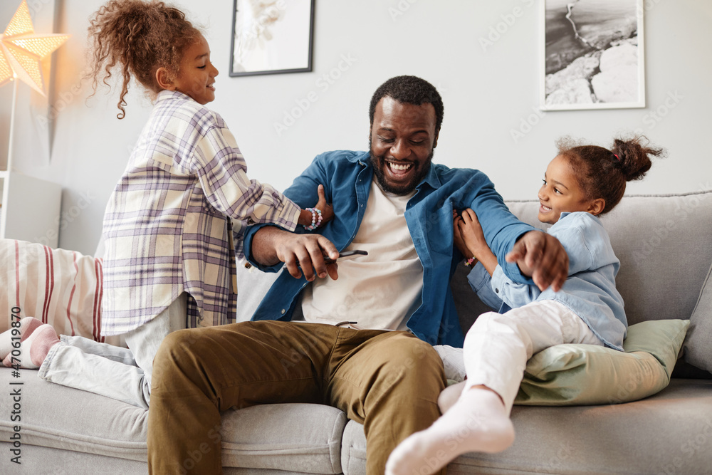 Portrait of two African-American girls playing with father in cozy home interior Portrait of two African-American girls playing with father in cozy home interior