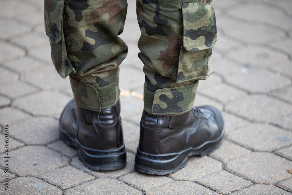 A military man dressed in moro pants and leather boots stands on a cobblestone. A military man dressed in moro pants and leather boots stands on a cobblestone.