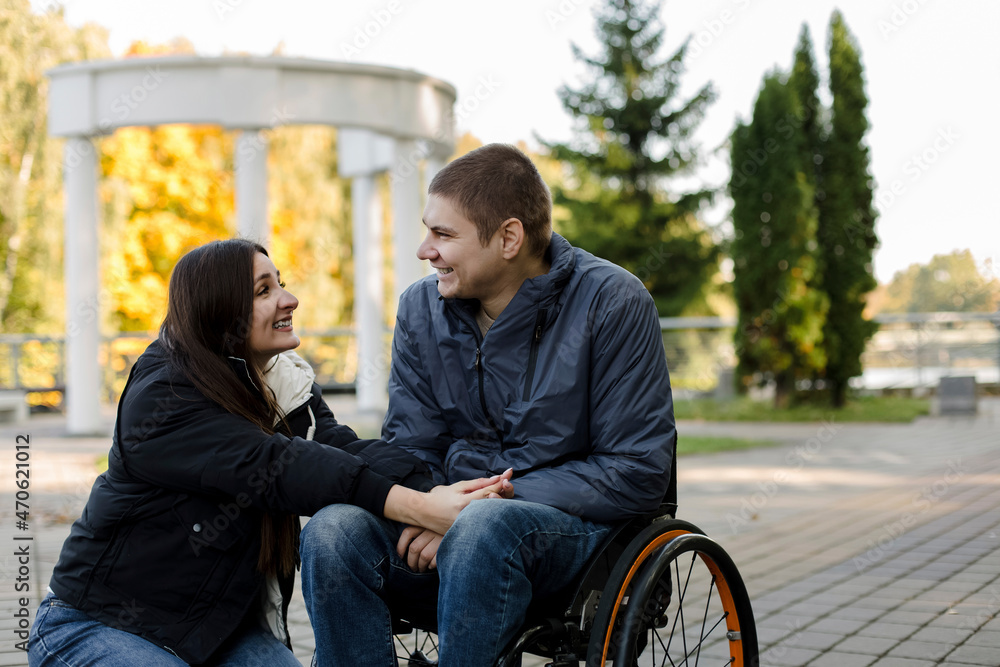 Girlfriend smiling at boyfriend sitting in wheelchair in park Girlfriend smiling at boyfriend sitting in wheelchair in park