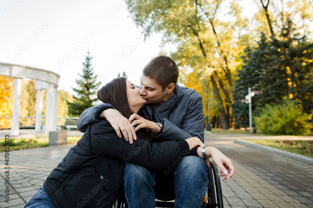 Boyfriend in wheelchair kissing girlfriend in park Boyfriend in wheelchair kissing girlfriend in park