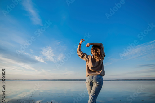 Woman with arms raised standing at lake
