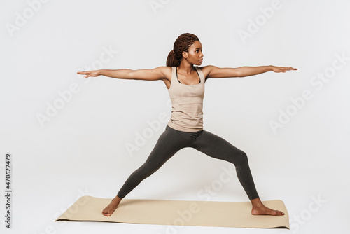 Young black woman doing exercise during yoga practice on mat