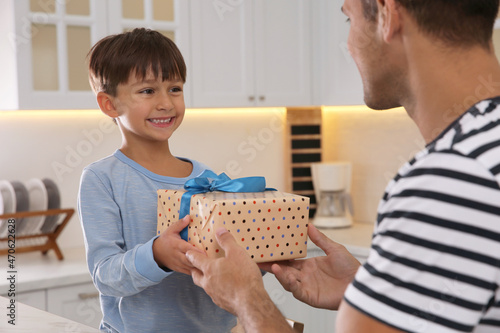 Billede på lærred Man receiving gift for Father's Day from his son in kitchen