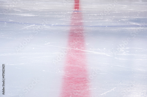 Clean empty ice hockey rink. Skate blade marks and snow crumbs. Marking lines are visible.