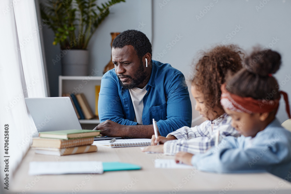 Portrait of caring father doing homework with two little girls in online school at home, copy space Portrait of caring father doing homework with two little girls in online school at home, copy space