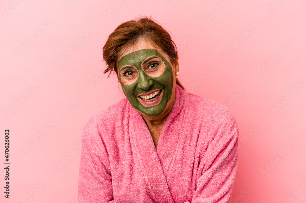 Middle age caucasian woman wearing a facial mask isolated on pink background laughing and having fun. Middle age caucasian woman wearing a facial mask isolated on pink background laughing and having fun.