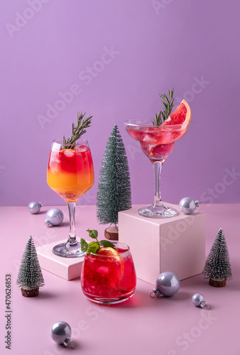 Festive citrus cocktails on podiums. Assortment of fresh Christmas drinks. Pink and red sangria cocktails, pomegranate  jingle and citrus tequila smashy. photo