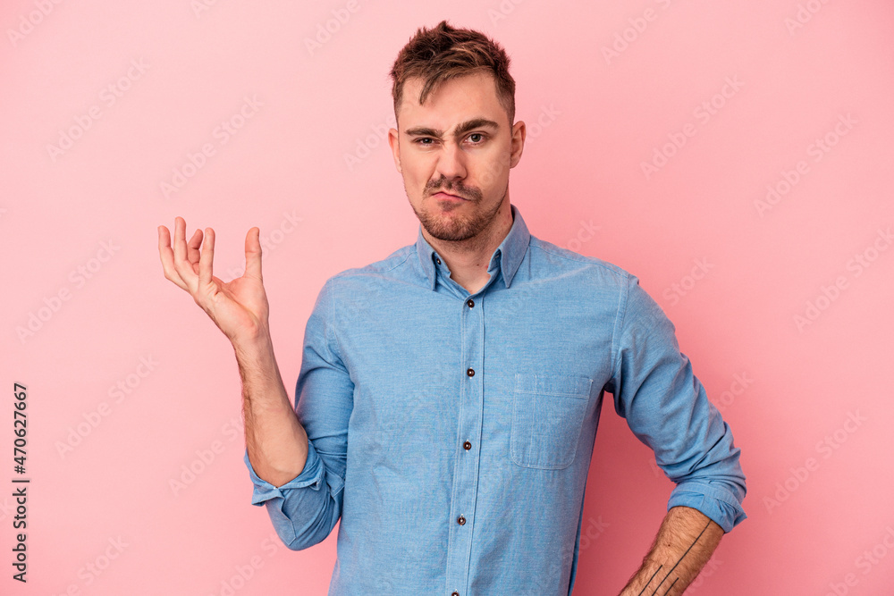 Young caucasian man isolated on pink background doubting and shrugging shoulders in questioning gesture. Young caucasian man isolated on pink background doubting and shrugging shoulders in questioning gesture.