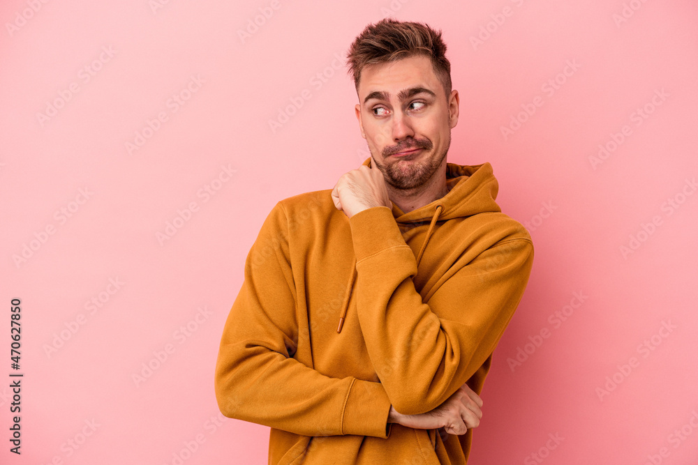 Fototapeta premium Young caucasian man isolated on pink background confused, feels doubtful and unsure.