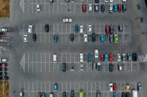 Cars are parked on asphalt parking with markings near the airport. Parking with lots of space is the top view. Aerial drone shot.