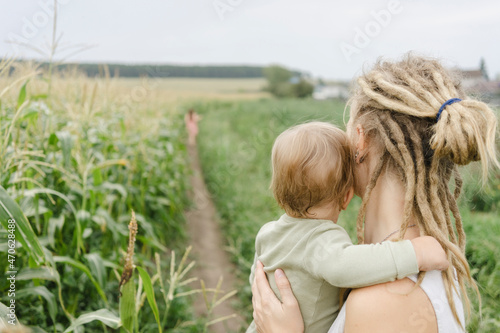 Woman with dreadlocks carrying toddler in corn field photo