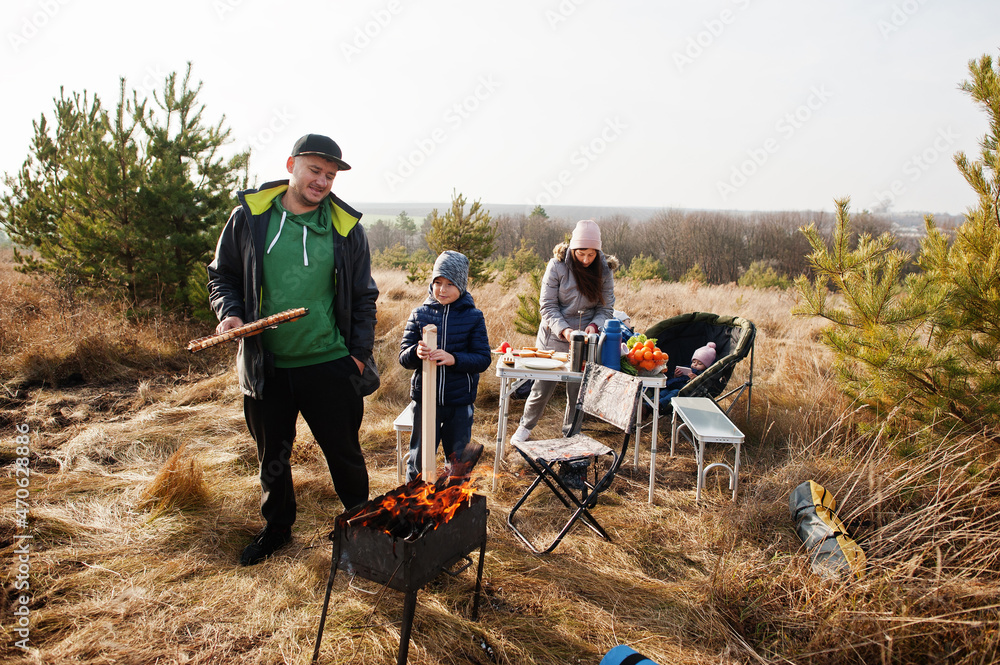 Family barbecuing on a deck in the pine forest. Bbq day with grill. Family barbecuing on a deck in the pine forest. Bbq day with grill.