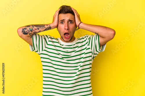 Young caucasian man with tattoos isolated on yellow background being shocked, she has remembered important meeting.