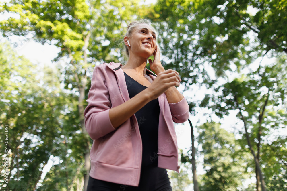 Woman in sports clothing adjusting in-ear headphones Woman in sports clothing adjusting in-ear headphones