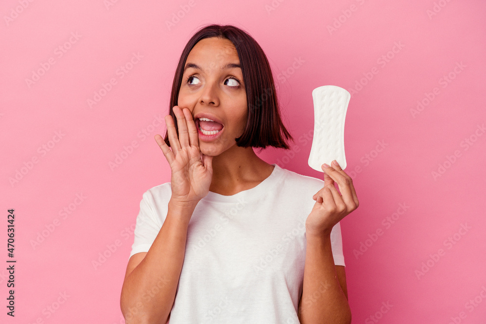 Young mixed race woman holding a compress isolated on pink background shouting and holding palm near opened mouth. Young mixed race woman holding a compress isolated on pink background shouting and holding palm near opened mouth.